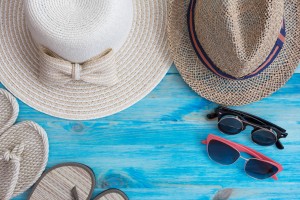 Summer hats and other travel accessories on blue wooden background